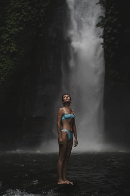 Woman in blue bikini standing before misty waterfall looking up, Bali Buleleng, Bali, Indonesia CR_YUKI260528-2037047-01 ,model released, Symbolfoto