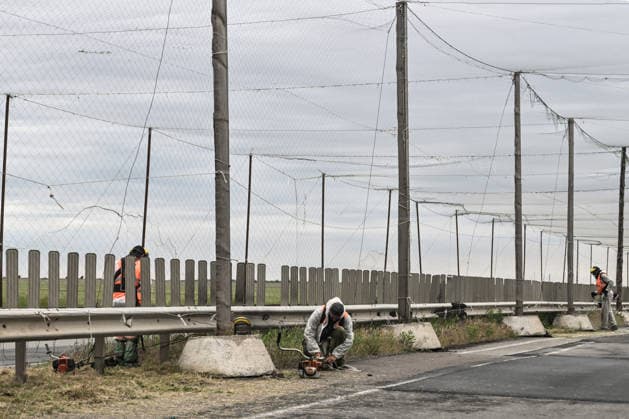 RECORD DATE NOT STATED Municipal workers mow grass along the roadside of the Mykolaiv–Kherson highway, above which anti-drone netting has been installed to protect against Russian FPV drones, Kherson region, Ukraine, on June 3, 2026. The Russian army attacks the city daily with FPV drones and other unmanned aerial vehicles, deliberately terrorizing civilians. Russian forces conduct hunts for local residents, tracking them with FPV drones and dropping explosives. Police officers, medics, public transport, and urban infrastructure are also targeted (Photo by Dmytro Smolienko Ukrinform) Life under shelling in frontline Kherson  Copyright: xDmytroxSmolienkox