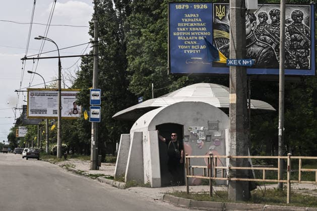 RECORD DATE NOT STATED A man stands at the entrance to a mobile concrete shelter installed at a public transport stop in the frontline city of Kherson, Ukraine, on June 2, 2026. The Russian army attacks the city daily with FPV drones and other unmanned aerial vehicles, deliberately terrorizing civilians. Russian forces conduct hunts for local residents, tracking them with FPV drones and _drop_ping explosives. Police officers, medics, public transport, and urban infrastructure are also targeted. Based on the intensity of attacks, Kherson is informally divided into yellow and red zones, with the red zone considered the most dangerous due to constant shelling and drone strikes. Anti-drone netting has been installed above roads to help protect against Russian  Copyright: xDmytroxSmolienkox