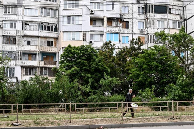RECORD DATE NOT STATED A man walks past a residential building damaged by Russian shelling in the frontline city of Kherson, Ukraine, on June 2, 2026. The Russian army attacks the city daily with FPV drones and other unmanned aerial vehicles, deliberately terrorizing civilians. Russian forces conduct hunts for local residents, tracking them with FPV drones and dropping explosives. Police officers, medics, public transport, and urban infrastructure are also targeted. Based on the intensity of attacks, Kherson is informally divided into yellow and red zones, with the red zone considered the most dangerous due to constant shelling and drone strikes. Anti-drone netting has been installed above roads to help protect against Russian FPV drone attacks (Photo by  Copyright: xDmytroxSmolienkox