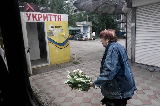 RECORD DATE NOT STATED A woman carrying a bouquet of mock-orange blossoms walks past a mobile concrete shelter in the frontline city of Kherson, Ukraine, on June 2, 2026. The Russian army attacks the city daily with FPV drones and other unmanned aerial vehicles, deliberately terrorizing civilians. Russian forces conduct hunts for local residents, tracking them with FPV drones and dropping explosives. Police officers, medics, public transport, and urban infrastructure are also targeted. Based on the intensity of attacks, Kherson is informally divided into yellow and red zones, with the red zone considered the most dangerous due to constant shelling and drone strikes. Anti-drone netting has been installed above roads to help protect against Russian FPV dron  Copyright: xDmytroxSmolienkox