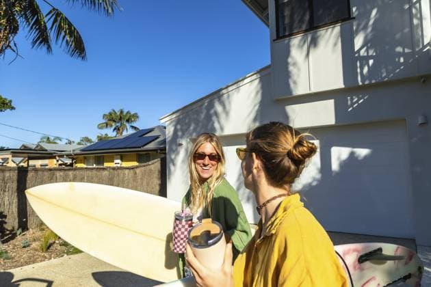 Zwei junge australische Surferinnen stehen draußen mit Surfbrettern, halten Getränke in der Hand und unterhalten sich unter dem strahlend sonnigen Himmel, um die Küstenkultur und den Sommergenuss zu genießen Two young australian women surfers standing outdoors with surfboards, holding beverages, and engaged in conversation under the bright sunny sky, embracing coastal culture and summer enjoyment Copyright: imageBROKER UnaixHuizi ibxuhu17689293.jpg ,model released, Symbolfoto ,property released