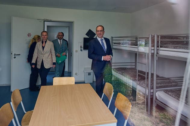Eroeffnung der Aussengrenzeinrichtung des Landes Brandenburg am Flughafen BER (Foto vom 12.06.2026; Innenminister Alexander Dobrindt besucht ein Mehrbettzimmer in der Einrichtung. Im Fenster spiegelt sich der Zaun um die Anlage). In der EU soll ein neues Asylsystem die Migration staerker regulieren. Dazu gehoert auch die Ueberpruefung bestimmer Antraege bereits an den Aussengrenzen. Eine Einrichtung dafuer gibt es jetzt am BER-Flughafen in Brandenburg. (Siehe epd-Meldung vom 12.06.2026) EDITORIAL USE ONLY *** Opening of Brandenburgs external border facility at BER Airport Photo from 12 06 2026 Interior Minister Alexander Dobrindt visits a multi-bed room in the facility The fence around the facility is reflected in the window In the EU, a ne Copyright: epd-bild ChristianxDitsch D26D0612ZABHFlughafenBER132238