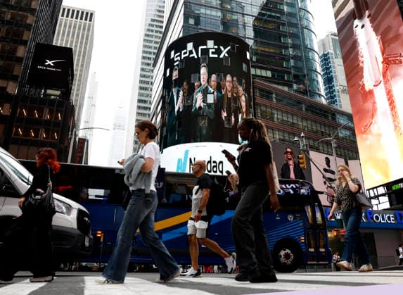 Pedestrians walk in Times Square with screens showing visuals of Elon Musk and SpaceX branding at the Nasdaq MarketSite Exchange in Times Square on Friday, June 12, 2026 in New York City. Elon Musk celebrated the Nasdaq opening bell Friday as SpaceX prepared to start trading publicly and possibly cementing his status as a trillionaire.  NYP20260612204 JOHNxANGELILLO