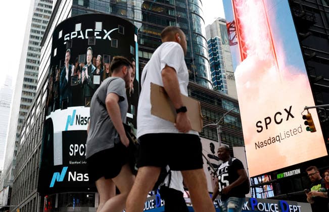 Spectators watch the screens in Times Square showing visuals of Elon Musk and SpaceX branding at the Nasdaq MarketSite Exchange in Times Square on Friday, June 12, 2026 in New York City. Elon Musk celebrated the Nasdaq opening bell Friday as SpaceX prepared to start trading publicly and possibly cementing his status as a trillionaire.  NYP20260612221 JOHNxANGELILLO