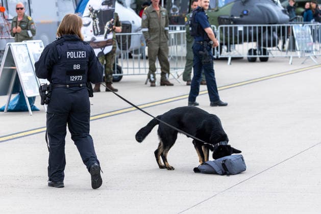 Fachbesuchertag auf ILA Berlin 2026, Berlin, 12.06.2026 Eine Polizeibeamtin (BB) führt einen Spürhund an einem herrenlosen Gepäckstück. Der schwarze Schäferhund beschnüffelt eine Tasche auf dem Vorfeld, im Hintergrund sind Bundeswehr-Personal und Militärgerät sichtbar. Schöneberg Berlin ExpoCenter Airport Brandenburg Deutschland *** Trade visitor day at ILA Berlin 2026, Berlin, 12 06 2026 A police officer BB leads a sniffer dog on a stray piece of luggage The black shepherd dog sniffs a bag on the apron, in the background are Bundeswehr personnel and military equipment Schöneberg Berlin ExpoCenter Airport Brandenburg Germany 20260612-1V9A1942-M4000