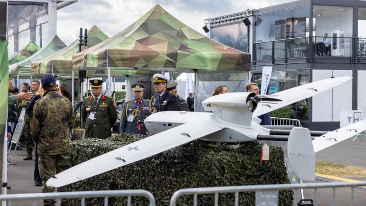 Fachbesuchertag auf ILA Berlin 2026, Berlin, 12.06.2026 Militärische Offiziere verschiedener Nationen begutachten eine unbemannte Aufklärungsdrohne (UAV) mit Bundeswehr-Markierung auf einem Freigelände-Ausstellungsstand. Die Drohne ist auf einem Tarnnetzsockel präsentiert, im Hintergrund Pavillons im Flecktarnmuster. Schöneberg Berlin ExpoCenter Airport Brandenburg Deutschland *** Trade visitor day at ILA Berlin 2026, Berlin, 12 06 2026 Military officers from various nations inspect an unmanned reconnaissance drone UAV with Bundeswehr markings on an open-air exhibition stand The drone is presented on a camouflage net base, in the background pavilions in spot camouflage Schöneberg Berlin ExpoCenter Airport Brandenburg Germany 20260612-286A9572-M4000