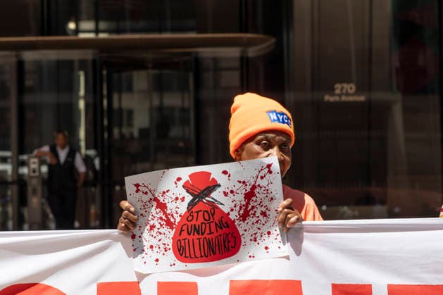June 12, 2026, New York, New York, USA: A coalition of organizations rally outside JP Morgan Chase headquarters in Midtown Manhattan to disrupt Chase CEO J. Dimon s party celebrating E. Musk s launch of SpaceX s IPO on the Nasdaq Stock Exchange and Musk s net worth as a trillionaire. A protester holds a sign that reads STOP FUNDING BIILLIONAIRES. Organizers denounce working people having SpaceX forced into their 401ks and pensions and the emergence of trillionaire-level wealth in the United States while millions of people face housing insecurity, medical debt, and low wages. New York USA - ZUMAr174 20260612_znp_r174_009 Copyright: xGinaxMxRandazzox
