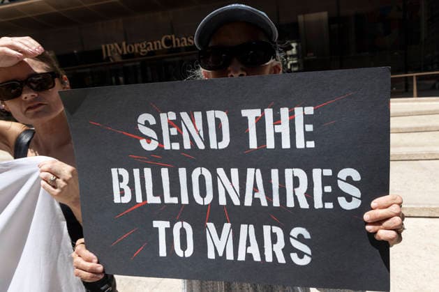 June 12, 2026, New York, New York, USA: A coalition of organizations rally outside JP Morgan Chase headquarters in Midtown Manhattan to disrupt Chase CEO J. Dimon s party celebrating E. Musk s launch of SpaceX s IPO on the Nasdaq Stock Exchange and Musk s net worth as a trillionaire. A protester holds a sign that reads SEND THE BILLIONAIRES TO MARS. Organizers denounce working people having SpaceX forced into their 401ks and pensions and the emergence of trillionaire-level wealth in the United States while millions of people face housing insecurity, medical debt, and low wages. New York USA - ZUMAr174 20260612_znp_r174_012 Copyright: xGinaxMxRandazzox