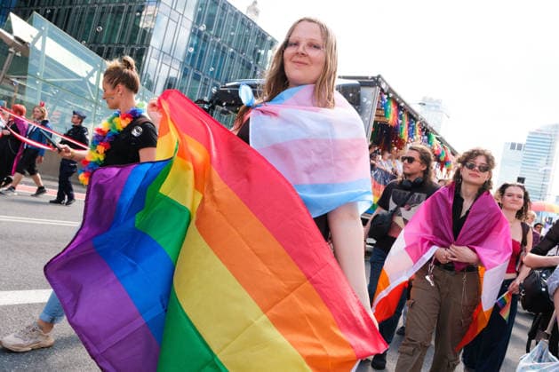 June 13, 2026, Warsaw, Masovian Voivodeship, Poland: A person draped in a trans pride flag carries a rainbow flag during the 25th annual Warsaw LGBTQ+ Pride Parade, known in Polish as the Equality Parade. LGBTQ+ people in Poland do not have the right to same-sex civil partnerships, marriage, and child adoption, while also facing homophobia and queerphobia from a largely conservative society. Therefore, the parade is organized primarily as a march for equal rights. Warsaw Poland  - ZUMAk204 20260613_zip_k204_007 Copyright: xRomanxKozielx