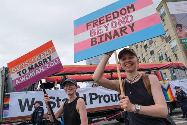 June 13, 2026, Warsaw, Masovian Voivodeship, Poland: A person holds up a sign in trans flag colors that reads freedom beyond binary (right) as another person holds a sign in lesbian flag colors that reads guys, I want to marry a woman too (left) during the 25th annual Warsaw LGBTQ+ Pride Parade, known in Polish as the Equality Parade. LGBTQ+ people in Poland do not have the right to same-sex civil partnerships, marriage, and child adoption, while also facing homophobia and queerphobia from a largely conservative society. Therefore, the parade is organized primarily as a march for equal rights. Warsaw Poland - ZUMAk204 20260613_zip_k204_025 Copyright: xRomanxKozielx
