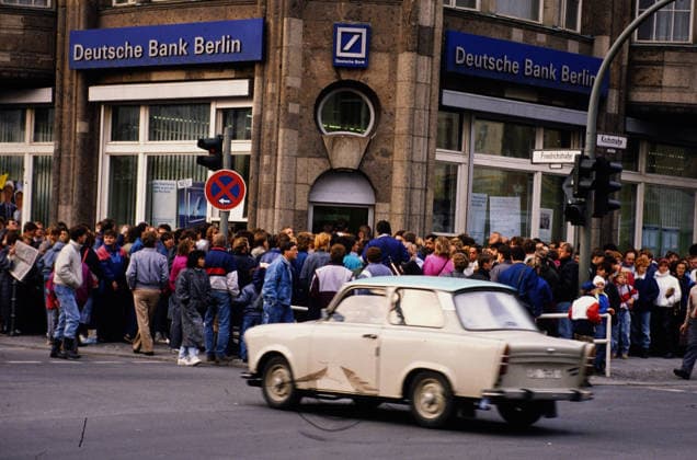 Ein Trabant fährt an einer Menschenmenge vor der Deutschen Bank in Berlin vorbei, wo DDR-Bürger ihr Begrüßungsgeld von 100 DM abholen. Die Szene zeigt den Geldwechsel nach dem Mauerfall, Deutschland, 1989. Berlin Berlin Deutschland *** a Trabant drives to a Crowd before the Germans Bank in Berlin over, where GDR Citizens their Welcome money from 100 DM Pick up the Scene shows the Money exchange to the Fall of the Wall, Germany, 1989 Berlin Berlin Germany Copyright: xUnitedxArchivesx xSvenxSimonxArchive SVS_94060000372
