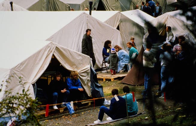 DDR-Flüchtlinge in einem provisorischen Zeltlager in Prag, einige sitzen in den Zelten, andere stehen oder sitzen davor, Tschechoslowakei, 1989. Berlin Berlin Deutschland *** GDR Refugees in a Provisional Tent camp in Prague, some sit in the Camping, other Standing Or sit before that, Czechoslovakia, 1989 Berlin Berlin Germany Copyright: xUnitedxArchivesx xSvenxSimonxArchive SVS_94060000375