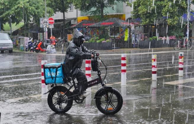 14.06.2026, Berlin - Deutschland. Ein Bote vom Lieferdienst Wolt unterwegs bei starkem Regen. *** 14 06 2026, Berlin Germany A messenger from the Wolt delivery service on the road in heavy rain