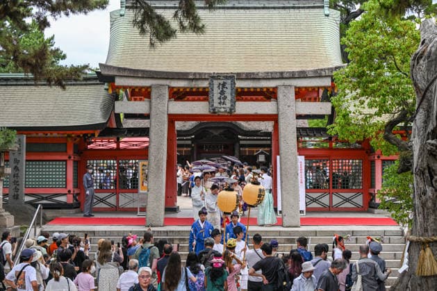 Osaka Keeps Centuries Old Otaue Rice Festival alive OSAKA, JAPAN - JUNE 14: A ceremonial procession walks along a red carpet and passes under a historic stone torii gate as it exits the main pavilion grounds during the Otaue Rice Planting Festival (Otaue Shinji) at Sumiyoshi Taisha Shrine in southern Osaka, Japan, on June 14, 2026. The ancient agricultural ritual, officially designated as an Important Intangible Folk Cultural Property of Japan, draws large crowds of local residents, photographers, and visitors who gather outside the gates to witness the costumed participants march toward the sacred paddy field to pray for a bountiful harvest. Artur Widak Anadolu Agency Anadolu Osaka Japan. Editorial use only. Please get in touch for any  Copyright: x2026xAnadoluxArturxWidak AnadoluxAgencyx