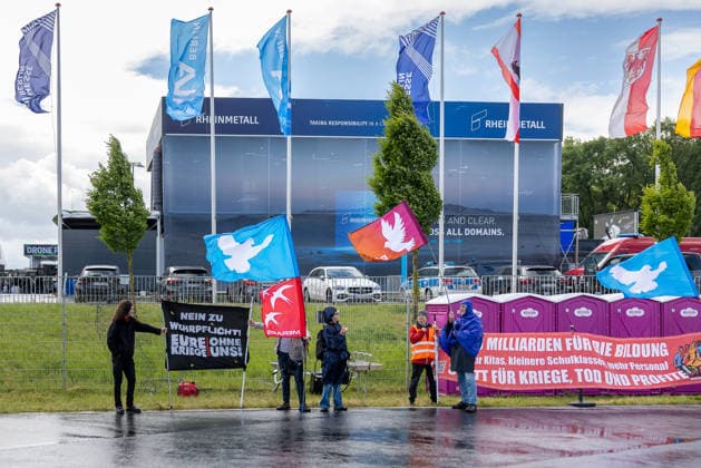 Publikumstag auf ILA Berlin 2026, Berlin, 14.06.2026 Demonstranten versammeln sich vor dem Messegelände und halten Friedenstauben-Fahnen sowie Transparente mit Aufschriften wie Nein zu Wehrpflicht und Milliarden für die Bildung . Im Hintergrund ist der Rheinmetall-Pavillon der Messe sichtbar. Bei wechselhaftem Wetter mit Starkregen und Sonnenschein protestiert die Gruppe gegen Rüstung und Aufrüstung. Schöneberg Berlin ExpoCenter Airport Brandenburg Deutschland *** Public day at ILA Berlin 2026, Berlin, 14 06 2026 Demonstrators gather in front of the exhibition grounds and hold peace dove flags and banners with inscriptions such as No to conscription and billions for education The Rheinmetall pavilion of the trade fair is visible in 20260614-286A0277-M4000