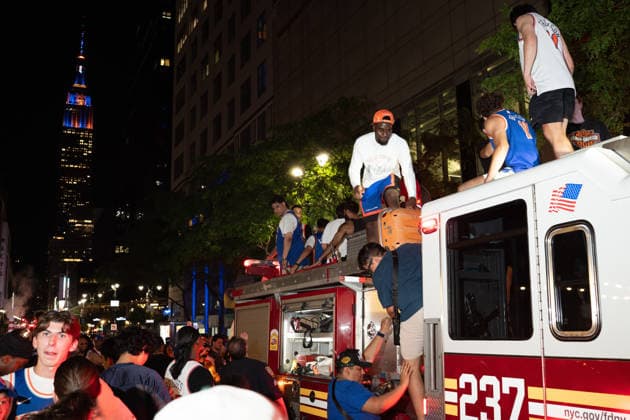 June 14, 2026, New York, New York, USA: Fans of the New York Knicks climb atop an FDNY fire engine with the Empire State building, lit blue and orange, in the background. New York USA  - ZUMAf193 20260614_znp_f193_009 Copyright: xDerekxFrenchx