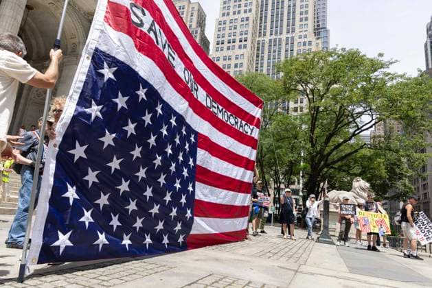 June 14, 2026, New York, New York, USA: Demonstrators join Rise and Resist s We Are In A State Of Emergency Flag Day anti-Trump protest on the steps of the New York Public Library (NYPL) branch on Fifth Avenue in Midtown Manhattan where a giant upside down flag is hoisted reading SAVE OUR DEMOCRACY. New York USA  - ZUMAr174 20260614_znp_r174_001 Copyright: xGinaxMxRandazzox