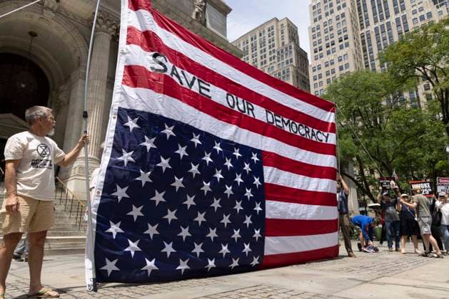 June 14, 2026, New York, New York, USA: Demonstrators join Rise and Resist s We Are In A State Of Emergency Flag Day anti-Trump protest on the steps of the New York Public Library (NYPL) branch on Fifth Avenue in Midtown Manhattan where a giant upside down flag is hoisted reading SAVE OUR DEMOCRACY. New York USA - ZUMAr174 20260614_znp_r174_002 Copyright: xGinaxMxRandazzox