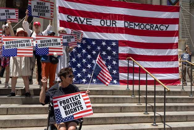 June 14, 2026, New York, New York, USA: Demonstrators join Rise and Resist s We Are In A State Of Emergency Flag Day anti-Trump protest on the steps of the New York Public Library (NYPL) branch on Fifth Avenue in Midtown Manhattan where a giant upside down flag is hoisted reading SAVE OUR DEMOCRACY. People hold signs that read PROTECT VOTING RIGHTS DEFEND THE CONSTITUTION REPRODUCTIVE JUSTICE FOR ALL MOST CORRUPT PRESIDENT EVER NO JIM CROW 2.0. New York USA - ZUMAr174 20260614_znp_r174_007 Copyright: xGinaxMxRandazzox