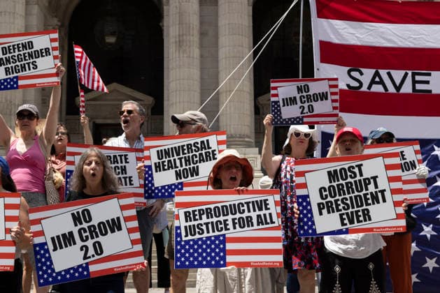 June 14, 2026, New York, New York, USA: Demonstrators join Rise and Resist s We Are In A State Of Emergency Flag Day anti-Trump protest on the steps of the New York Public Library (NYPL) branch on Fifth Avenue in Midtown Manhattan. People have upside down flags and signs that read REPRODUCTIVE JUSTICE FOR ALL MOST CORRUPT PRESIDENT EVER UNIVERSAL HEALTHCARE NOW NO JIM CROW 2.0. New York USA - ZUMAr174 20260614_znp_r174_011 Copyright: xGinaxMxRandazzox