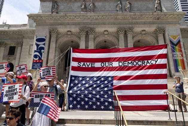 June 14, 2026, New York, New York, USA: Demonstrators join Rise and Resist s We Are In A State Of Emergency Flag Day anti-Trump protest on the steps of the New York Public Library (NYPL) branch on Fifth Avenue in Midtown Manhattan where a giant upside down flag is hoisted reading SAVE OUR DEMOCRACY. People hold signs that read PROTECT VOTING RIGHTS MOST CORRUPT PRESIDENT EVER NO JIM CROW 2.0. New York USA - ZUMAr174 20260614_znp_r174_014 Copyright: xGinaxMxRandazzox