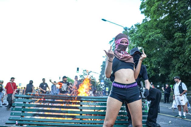 June 14, 2026, Geneva, Switzerland, European Union: A female masked protester stands in front of a burning bench showing her middle fingers with both hands during demonstrations in Geneva ahead of the G7 summit, which begins tomorrow in Evian-les-Bains. Geneva European Union  - ZUMAo116 20260614_znp_o116_024 Copyright: xBiancaxOterox