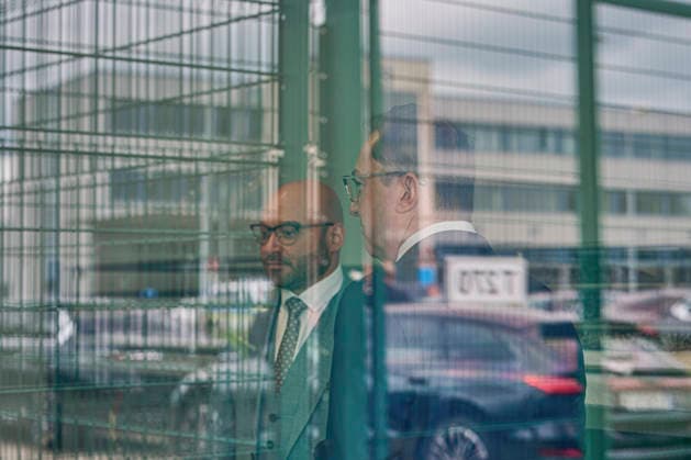 Eroeffnung der Aussengrenzeinrichtung des Landes Brandenburg am BER-Flughafen (Foto vom 12.06.2026: Innenminister Alexander Dobrindt (CSU); Rene Wilke (SPD), Minister fuer Arbeit, Soziales, Gesundheit und gesellschaftlichen Zusammenhalt des Landes Brandenburg, in einem der Zimmer des Abschiebegewahrsam. Im Fenster spiegelt sich der Zaun um die Anlage und Flughafengebaeude). In der EU soll ein neues Asylsystem die Migration staerker regulieren. Dazu gehoert auch die Ueberpruefung bestimmer Antraege bereits an den Aussengrenzen. Eine Einrichtung dafuer gibt es jetzt am BER-Flughafen in Brandenburg. (Siehe epd-Meldung vom 12.06.2026) EDITORIAL USE ONLY *** Opening of the State of Brandenburg’s external border facility at BER Airport. Photo ta Copyright: epd-bild ChristianxDitsch D26D0612ZABHFlughafenBER132521