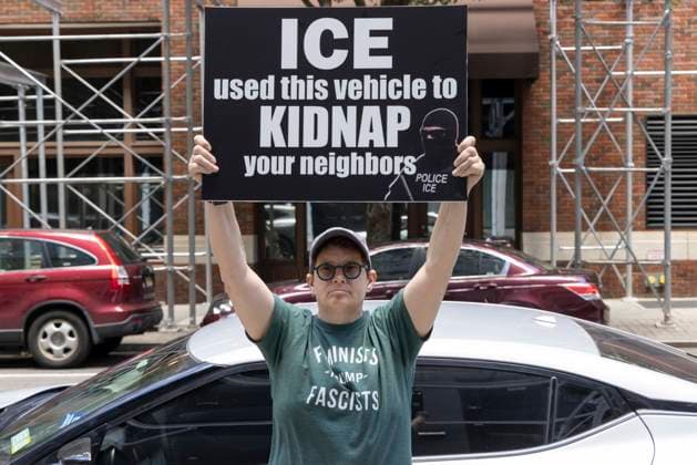June 15, 2026, New York, New York, USA: An anti-ICE (Immigration Customs and Enforcement) demonstrator holds a sign reading ICE used this vehicle to KIDNAP your neighbors with an image of a masked agent wearing a vest that reads POLICE ICE, identifying a car parked on the street near the Department of Justice Immigration Courts at 201 Varick Street. Recently Border Czar T. Homan threatened to send a surge of immigration agents to New York City after Governor Hochul signed legislation barring state and local law enforcement from working with immigration in New York jails. New York USA - ZUMAr174 20260615_znp_r174_004 Copyright: xGinaxMxRandazzox