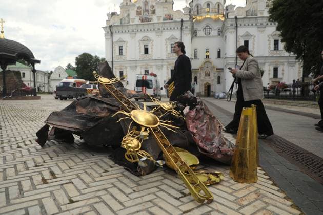 People walk past an old gilded cross, deformed by the blast wave, and pieces of burnt metal plating, lying on the ground outside the Dormition Cathedral at the Kyiv Pechersk Lavra, which was hit by a Russian drone during a massive attack on the Ukrainian capital on Monday night, June 15, Kyiv, Ukraine, June 16, 2026. The strike triggered a large-scale fire that covered about 800 sq m and damaged 80% of the roof structure. (Photo by Yuliia Ovsiannikova Ukrinform) Briefing on aftermath of Russian attack on cultural heritage sites of Kyiv  Copyright: xYuliiaxOvsiannikovax
