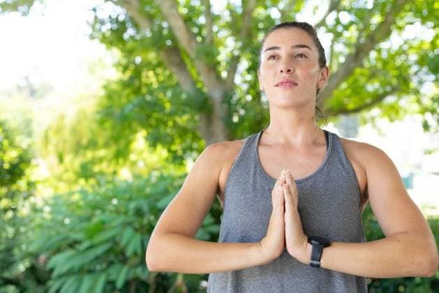 Adult female standing at right in park praying in gray tank, black smartwatch, copy space, model released, property released, 11.12.2025 06:00:00, 15055846 Copyright: xIMS-260616xcreatorid:x393x 15055846