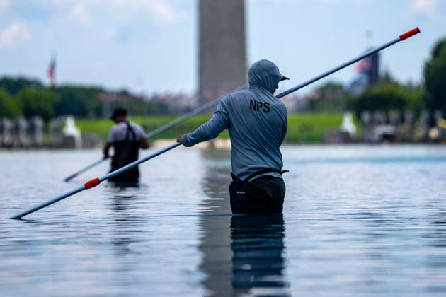U.S. National Park Service employees use a vacuum pump to clean algae off the bottom of the newly repainted Lincoln Memorial Reflecting Pool on the National Mall in Washington, DC on Wednesday, June 17, 2026. The Trump Administration spent $16 million to paint the bottom of the pool American flag blue and as part of an effort to repair Washington landmarks in for preparation the country s 250th birthday this summer.  WAP20260617301 BONNIExCASH