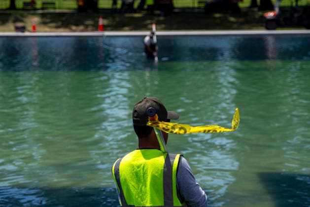 U.S. National Park Service employees use a vacuum pump to clean algae off the bottom of the newly repainted Lincoln Memorial Reflecting Pool on the National Mall in Washington, DC on Wednesday, June 17, 2026. The Trump Administration spent $16 million to paint the bottom of the pool American flag blue and as part of an effort to repair Washington landmarks in for preparation the country s 250th birthday this summer.  WAP20260617305 BONNIExCASH