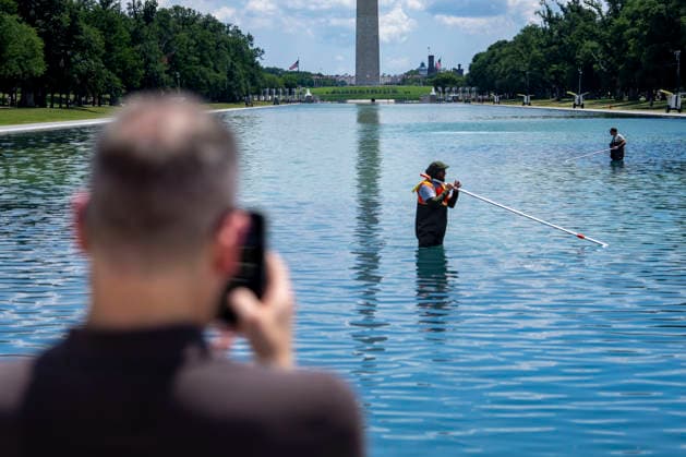 A man takes pictures as U.S. National Park Service employees uses a vacuum pump to clean algae off the bottom of the newly repainted Lincoln Memorial Reflecting Pool on the National Mall in Washington, DC on Wednesday, June 17, 2026. The Trump Administration spent $16 million to paint the bottom of the pool American flag blue and as part of an effort to repair Washington landmarks in for preparation the country s 250th birthday this summer.  WAP20260617310 BONNIExCASH