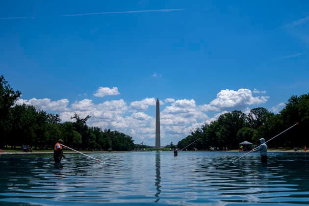 U.S. National Park Service employees use a vacuum pump to clean algae off the bottom of the newly repainted Lincoln Memorial Reflecting Pool on the National Mall in Washington, DC on Wednesday, June 17, 2026. The Trump Administration spent $16 million to paint the bottom of the pool American flag blue and as part of an effort to repair Washington landmarks in for preparation the country s 250th birthday this summer.  WAP20260617312 BONNIExCASH