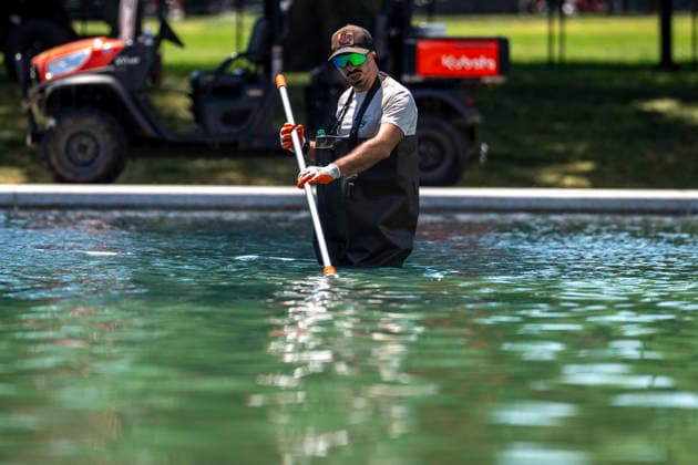 A U.S. National Park Service employee uses a vacuum pump to clean algae off the bottom of the newly repainted Lincoln Memorial Reflecting Pool on the National Mall in Washington, DC on Wednesday, June 17, 2026. The Trump Administration spent $16 million to paint the bottom of the pool American flag blue and as part of an effort to repair Washington landmarks in for preparation the country s 250th birthday this summer.  WAP20260617318 BONNIExCASH