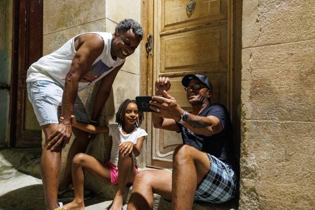 CUBA-HAVANA SOCIAL CRISIS AND WORLD CUP HAVANA, CUBA - JUNE 16, 2026: A family sits in a doorway, smiling while watching the live broadcast of the Argentina versus Algeria World Cup football game on a mobile phone screen in Old Havana, Cuba, on June 16, 2026. Sharing small screens on doorsteps has become a common way for families to enjoy entertainment together during power outages. (Photo by Pablo Miranzo JNA Press via Nexpher Images) HAVANA