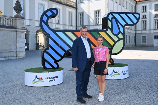 Markus SOEDER (Ministerpraesident Bayern und CSU Vorsitzender), Jessica BREDOW WERNDL vor dem Maskottchen,Olympia Dackel. Pressetermin im Rahmen der Einladung der Olympischen Spitzenverbaende zur Vorstellung des vertieften Bewerbungskonzepts Muenchen 20XX am Donnerstag, 18.06.2026 vor dem Schloss Nymphenburg *** Markus SOEDER, Minister-President of Bavaria and CSU Chairman, Jessica BREDOW WERNDL in front of the mascot, Olympia the Dachshund, at a press event held as part of the invitation extended by the leading Olympic federations to present the detailed bid concept for Munich 20XX on Thursday, June 18, 2026, in front of Nymphenburg Palace,detected_source_language