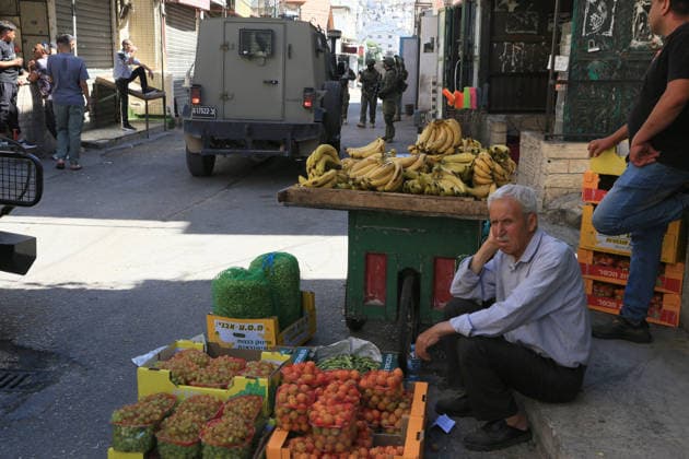 June 18, 2026, Nablus, West Bank, Palestine: Israeli military vehicles are stationed in the center of the market while Palestinian vendors display fruits and vegetables during a raid on Balata refugee camp east of Nablus in the West Bank. Israeli forces raided the central market during a security operation. Palestinian sources said that the army arrested seven Palestinians from various neighborhoods in Nablus and its surrounding refugee camps. Nablus Palestine - ZUMAs197 20260618_aaa_s197_020 Copyright: xNasserxishatyehx