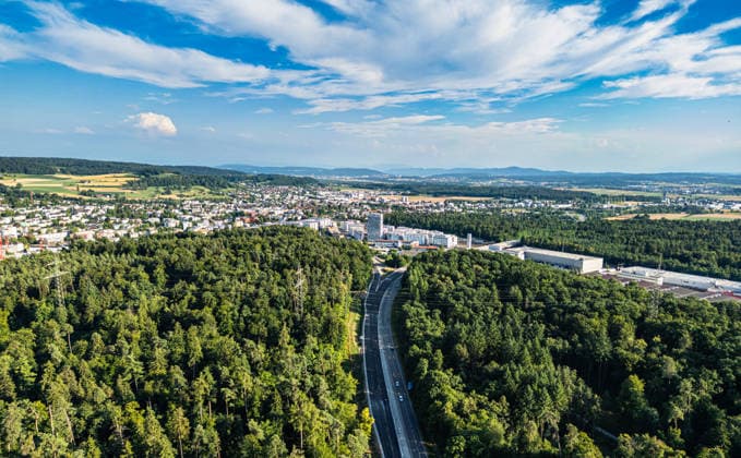 Drone footage of the major infrastructure construction site in G Bülach, Switzerland, 5th Jul 2025: View across the Hardwald forest and the extension of Schaffhauserstrasse into the access road, with the city of Bülach behind it. *** Drone footage of the major infrastructure construction site in G Bülach, Switzerland, July 5, 2025. View across the Hardwald forest and the extension of Schaffhauserstrasse into the access road, with the city of Bülach in the background,detected_source_language Copyright: xAndreasxHaasx