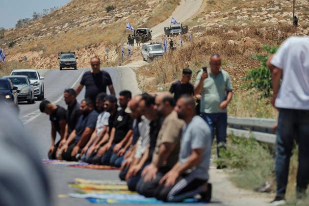 Protest Against Settlers in Dura Palestinian men kneel on prayer rugs during Friday prayers on a road near Israeli soldiers and military vehicles in Jabal Tarousa near Dura, south of Hebron, in the occupied West Bank, on June 19, 2026. Palestinians held the prayers to protest the establishment of a newly built Israeli settlement outpost and the seizure of land. Israeli forces later fired tear gas to suppress the gathering, allegedly causing several people, including journalists, to suffer from inhalation. Dura West Bank Palestinian Territories Copyright: xMosabxShawerx