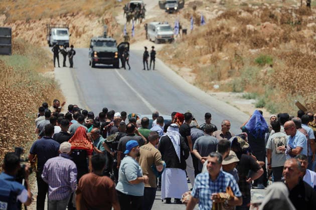 Protest Against Settlers in Dura Armed Israeli soldiers stand near a military vehicle facing a crowd of Palestinian men on a road in Jabal Tarousa near Dura, south of Hebron, in the occupied West Bank, on June 19, 2026. Palestinians held Friday prayers to protest the establishment of a newly built Israeli settlement outpost and the seizure of land. Israeli forces later fired tear gas to suppress the gathering, allegedly causing several people, including journalists, to suffer from inhalation. Dura West Bank Palestinian Territories Copyright: xMosabxShawerx
