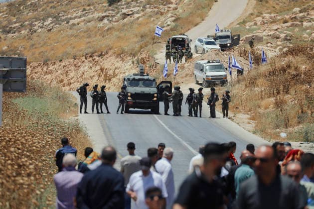 Protest Against Settlers in Dura Armed Israeli soldiers stand near a military vehicle facing a crowd of Palestinian men on a road in Jabal Tarousa near Dura, south of Hebron, in the occupied West Bank, on June 19, 2026. Palestinians held Friday prayers to protest the establishment of a newly built Israeli settlement outpost and the seizure of land. Israeli forces later fired tear gas to suppress the gathering, allegedly causing several people, including journalists, to suffer from inhalation. Dura West Bank Palestinian Territories Copyright: xMosabxShawerx