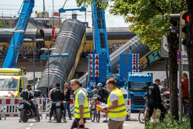 Schweres Güterzug-Unglück in München, Bergung eines Waggons, der von der Brücke gestürzt ist, Samstagmittag, München, 20.. Juni 2026 Deutschland, München, 20. Juni 2026, schweres Güterzug-Unglück in München, ein Toter, zwei Kräne bergen einen Waggon, der in der Nacht von der Brücke gestürzt ist, Schaulustige verfolgen die Bergungsarbeiten am Samstagmittag, das Zugunglück hatte sich nachts um 1:40 Uhr ereignet, zwei Güterzüge stießen beim Rangieren zusammen, Waggons stürzten von der Brücke, ein Mensch wurde tödlich verletzt, die Schleißheimer Straße, ist in diesem Bereich gesperrt, Milbertshofen, Verkehr, Bahn, Bayern, *** Serious freight train accident in Munich; recovery of a railcar that fell off a bridge; Saturday a