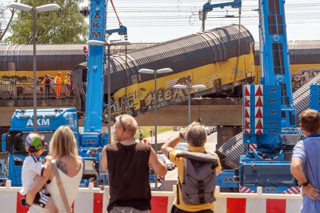 Schweres Güterzug-Unglück in München, Bergung eines Waggons, der von der Brücke gestürzt ist, Samstagmittag, München, 20.. Juni 2026 Deutschland, München, 20. Juni 2026, schweres Güterzug-Unglück in München, ein Toter, zwei Kräne bergen einen Waggon, der in der Nacht von der Brücke gestürzt ist, Schaulustige verfolgen die Bergungsarbeiten am Samstagmittag, das Zugunglück hatte sich nachts um 1:40 Uhr ereignet, zwei Güterzüge stießen beim Rangieren zusammen, Waggons stürzten von der Brücke, ein Mensch wurde tödlich verletzt, die Schleißheimer Straße, ist in diesem Bereich gesperrt, Milbertshofen, Verkehr, Bahn, Bayern, *** Serious freight train accident in Munich; recovery of a railcar that fell off a bridge; Saturday a