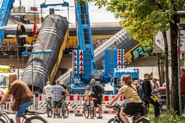 Schweres Güterzug-Unglück in München, Bergung eines Waggons, der von der Brücke gestürzt ist, Samstagmittag, München, 20.. Juni 2026 Deutschland, München, 20. Juni 2026, schweres Güterzug-Unglück in München, ein Toter, zwei Kräne bergen einen Waggon, der in der Nacht von der Brücke gestürzt ist, Schaulustige verfolgen die Bergungsarbeiten am Samstagmittag, das Zugunglück hatte sich nachts um 1:40 Uhr ereignet, zwei Güterzüge stießen beim Rangieren zusammen, Waggons stürzten von der Brücke, ein Mensch wurde tödlich verletzt, die Schleißheimer Straße, ist in diesem Bereich gesperrt, Milbertshofen, Verkehr, Bahn, Bayern, *** Serious freight train accident in Munich; recovery of a railcar that fell off a bridge; Saturday a