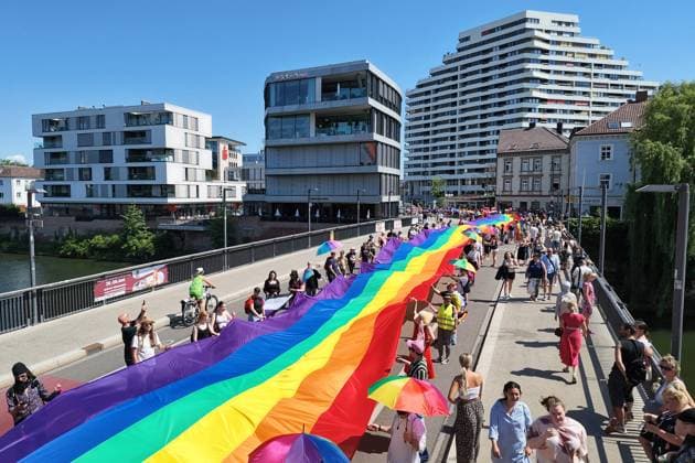 Teilnehmende tragen beim Christopher Street Day (CSD) eine ueber 100 Meter lange und 4,2 Meter breite Regenbogenfahne ueber die Herdbruecke, die das in Baden-Wuerttemberg gelegenen Ulm mit dem in Bayern gelegenen Neu-Ulm verbindet (Foto vom 20.06.2026). Die Veranstalter bezeichnen sie als die groesste Regenbogenfahne Deutschlands. Der CSD steht in diesem Jahr unter dem Motto Von Ufer zu Ufer: Wir halten zusammen! und findet zum 15. Mal statt. EDITORIAL USE ONLY *** During Christopher Street Day (CSD), participants carry a rainbow flag over 100 meters long and 4.2 meters wide across the Herdbruecke, which connects Ulm, located in Baden-Württemberg, with Neu Ulm, located in Bavaria. Photo from June 20, 2026. The organizers describe it as th Copyright: epd-bild ThomasxHeckmann 2