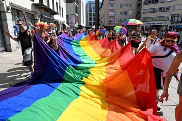 Teilnehmende tragen beim Christopher Street Day (CSD) in Ulm und Neu-Ulm eine ueber 100 Meter lange und 4,2 Meter breite Regenbogenfahne (Foto vom 20.06.2026). Die Veranstalter bezeichnen sie als die groesste Regenbogenfahne Deutschlands. Der CSD steht in diesem Jahr unter dem Motto Von Ufer zu Ufer: Wir halten zusammen! und findet zum 15. Mal statt. EDITORIAL USE ONLY *** Participants at Christopher Street Day (CSD) in Ulm and Neu Ulm are carrying a rainbow flag over 100 meters long and 4.2-meter-wide rainbow flag. Photo taken on June 20, 2026. The organizers describe it as Germany’s largest rainbow flag. This year’s CSD is themed From Shore to Shore Copyright: epd-bild ThomasxHeckmann 260620_Heckmann_Ulm_CSD_Regenbogenfahne_2414