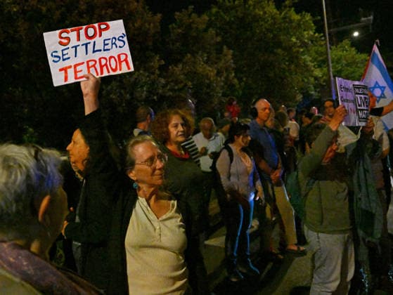 A woman holds a placard reading :Stop Settler s Terror at a protest against Israeli Prime Minister Benjamin Netanyahu in Jerusalem on Saturday, June 20, 2026. U.S. President Donald Trump has called on Prime Minister Netanyahu to stop the military strikes in Lebanon.  JER2026062004 DEBBIExHILL