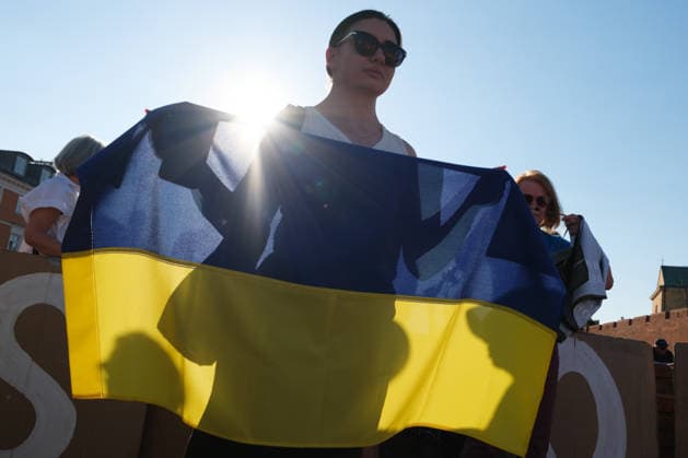 June 20, 2026, Warsaw, Masovian Voivodeship, Poland: A woman holds a Ukrainian flag during a demonstration on Warsaw s Castle Square for World Refugee Day. Organized under the slogan open republic, the rally was held in protest against growing xenophobia towards migrants and refugees in Poland, as well as the increasing use of anti-migrant rhetoric by Polish conservatives and far-right politicians. Warsaw Poland - ZUMAk204 20260620_zip_k204_032 Copyright: xRomanxKozielx